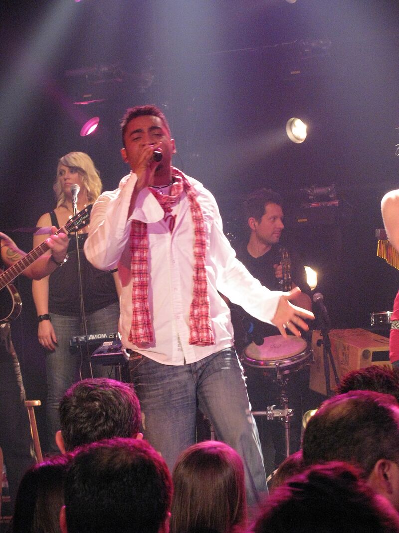 Michael Lascar singt mit ausgestrecktem Arm am Mikrofon, hinter ihm die Band