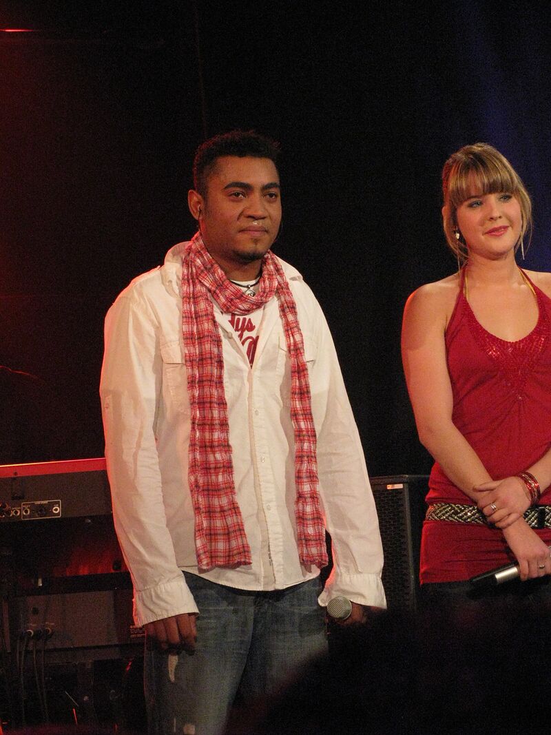Michael Lascar mit rot-weissem Schal und einer Sängerin auf der Bühne